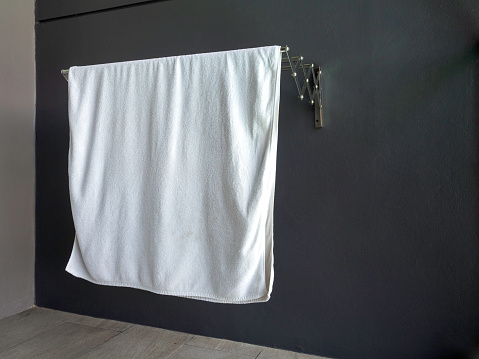 White dry clean towel hanging on towel rack on the wall on terrace in hotel room with copy space.