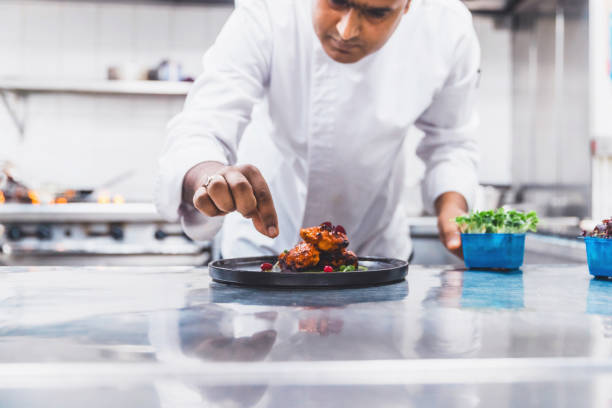 istock Professional Chef Platting Grilled Chicken Tikka in a Gourmet Kitchen 1305918171