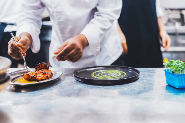 istock Professional Chef Platting Grilled Chicken Tikka in a Gourmet Kitchen 1305918251