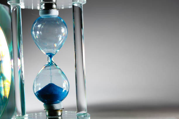 istock Blue hourglass on gray background close up 1305919544