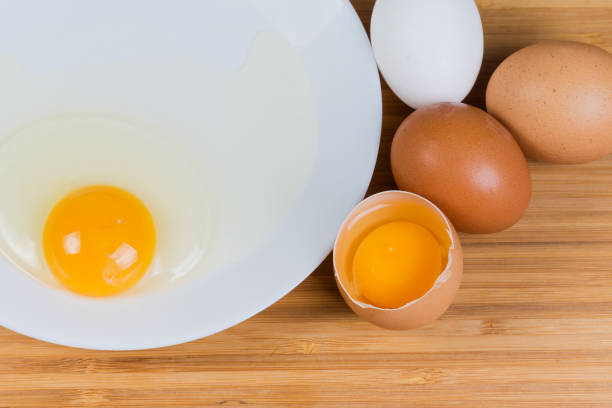 istock Whole and broken eggs on dish, top view close-up 1305919865