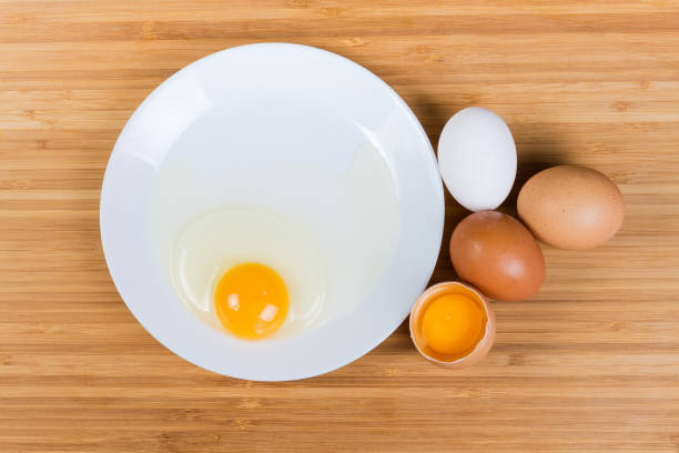istock Whole and broken eggs on dish on a wooden surface 1305919911