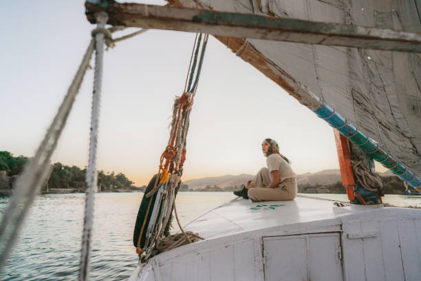 Woman traveling on felucca on the Nile at sunset Young Caucasian woman traveling on felucca on the Nile at sunset felucca boat stock pictures, royalty-free photos & images