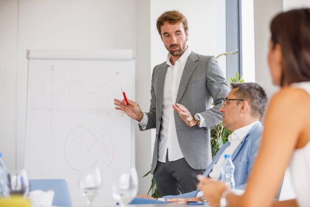 istock Young businessman discussing graphs drawn on flipchart with colleague 1305922497