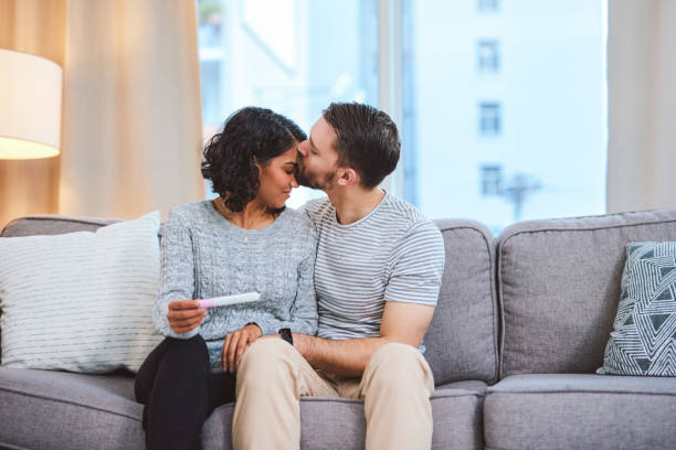 I can't wait to start this chapter with you Cropped shot of a happy young couple sitting on the sofa together and holding a positive pregnancy test indian couple kiss stock pictures, royalty-free photos & images