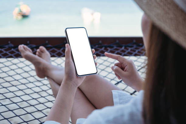 istock a woman holding mobile phone with blank desktop screen while lying down on hammock on the beach 1305926729
