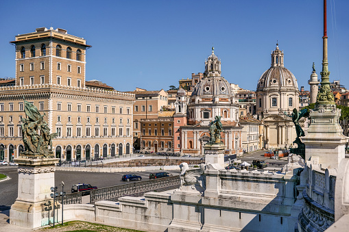 A portion of Piazza Venezia in the historic center of Rome from the Altare della Patria National Monument, in the heart of the Eternal City. In the foreground the domes of the church of Santa Maria di Loreto (center) and the church of the Santissimo Nome di Maria al Foro near the Roman Forum. The Altare della Patria, or Vittoriano, was built in 1885 in honor of the first King of Italy, Vittorio Emanuele II. Inside there is the Unknown Soldier grave, the National Memorial Monument dedicated to all Italian soldiers who died in wars. The Altare della Patria is the scene of all the official Italian celebrations, in particular the National Day of the Republic on June 2nd and the Liberation Day on April 25th. Image in high definition format.
