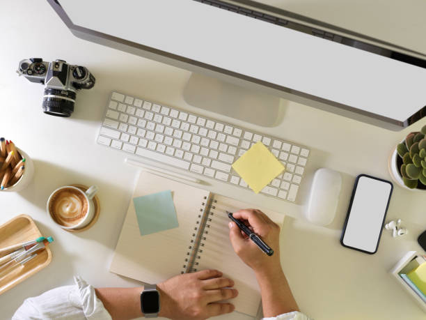 istock Businessman hand writing on blank notebook while working on computer desk with office supplies 1305928615
