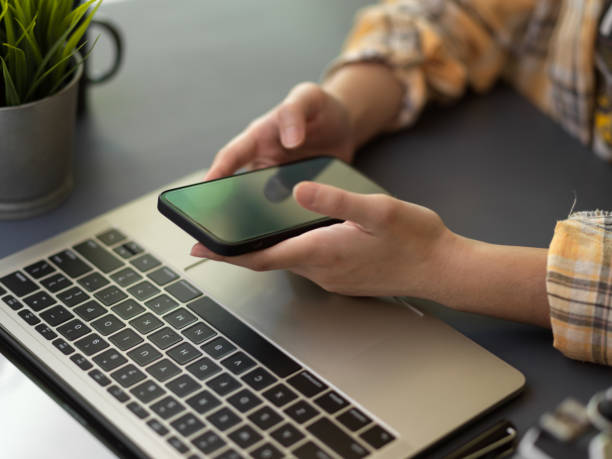 istock Female freelancer working smartphone and laptop on workspace in home office room 1305929709