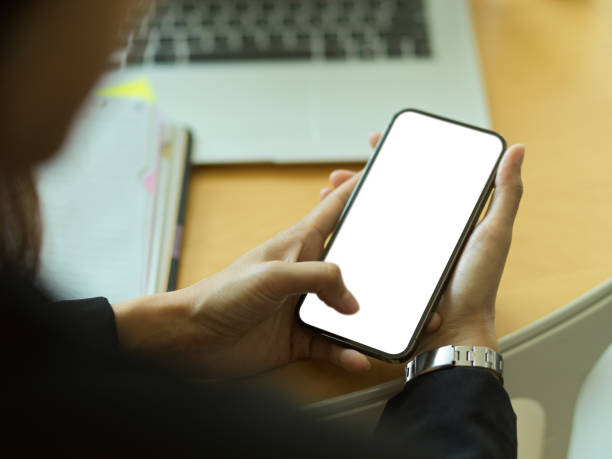 istock Businessperson hands using smartphone with mock up screen on workspace 1305929727
