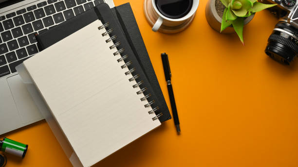 istock Stylish workspace with notebooks, pen, laptop, camera, coffee cup and plant pot on yellow table 1305929743