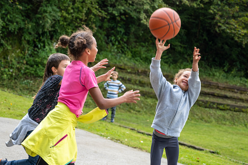 Two friends playing basketball. Both about 12 years old, African and Caucasian females.