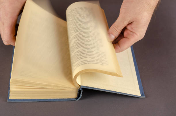 istock Blurred Motion Of Hand Turning Page Over gray Background. 1305932639