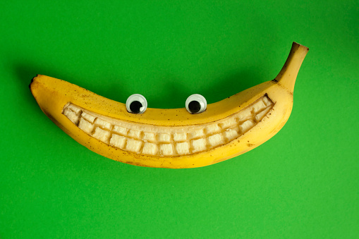 Banana with eyes and a smile on a green background