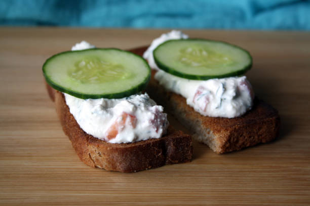 istock Cottage cheese dip with cucumber slices on black bread toast. Breakfast. 1305932787