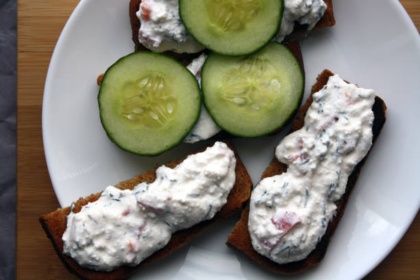 istock Cottage cheese dip with cucumber slices on black bread toast. Breakfast. 1305932813