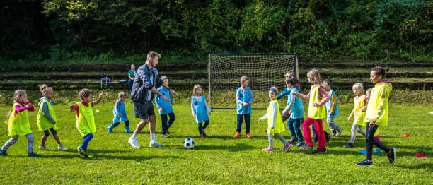 entrenador instruyendo a niños durante entrenamiento de fútbol - soccer child coach childhood fotografías e imágenes de stock