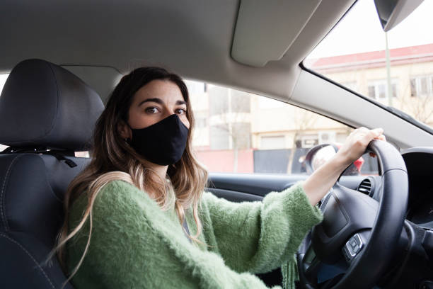 istock Woman driving car wearing protective mask. 1305935201