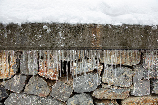 Large group of icicles on stone wall background