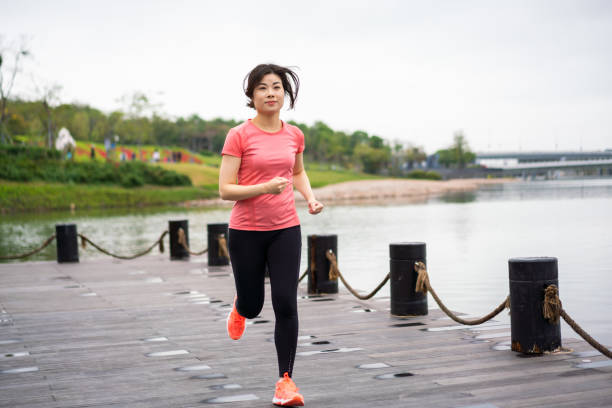 istock Asian woman jogging in a park 1305937633