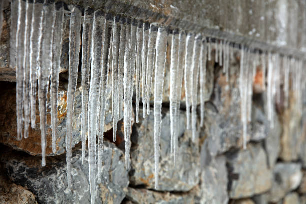 Large group of icicles on stone wall background