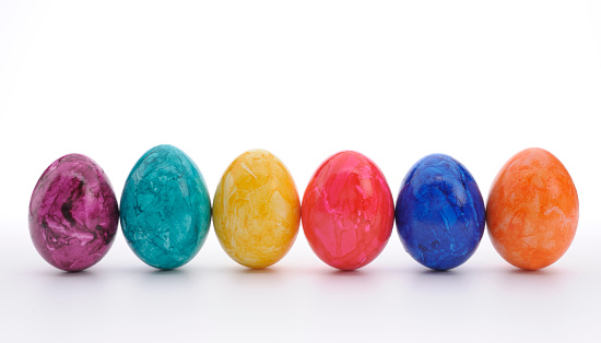 three colorful easter eggs in egg cups in front of a neutral background