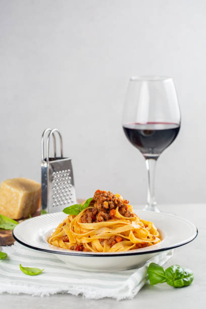 итальянская яичная паста с мясным соусом и бокалом красного вина. - dishware pasta tagliatelle beef стоковые фото и изображения