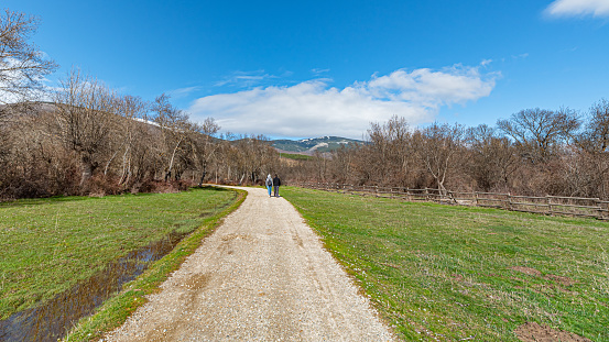 Lozoya del Valle, Madrid, Spain. Couple from a distance hiking on mountain trails on a sunny winter day