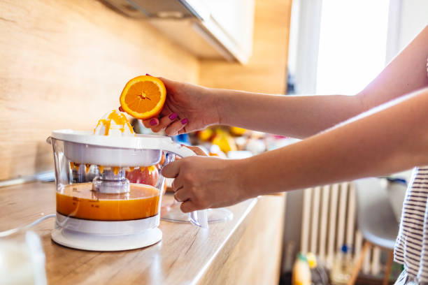 Young woman making orange juice in her kitchen