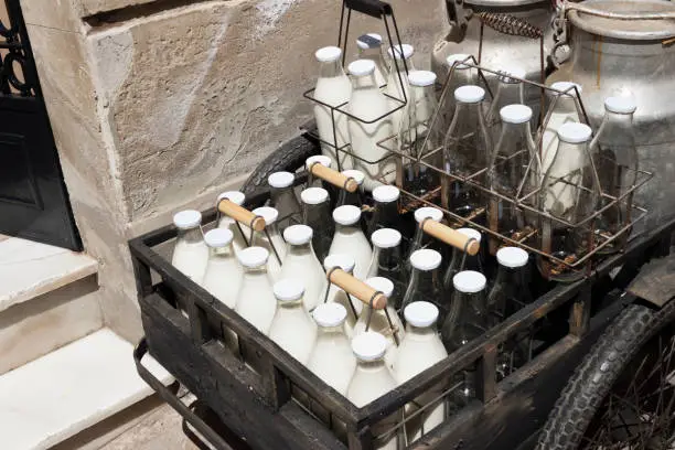 Bottles and aluminum cans of milk for delivery in vintage rusty milkman bicycle.