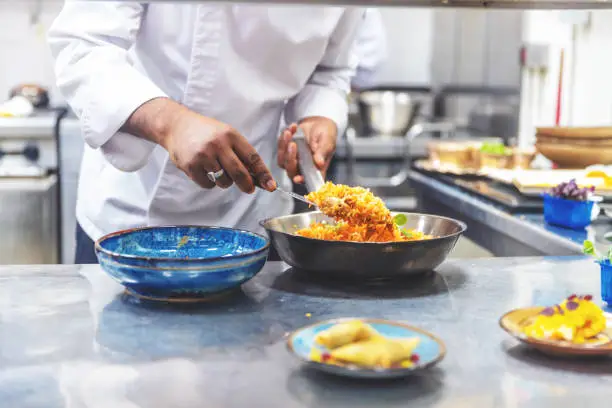 Professional chef platting Chicken Biryani at an Indian Restaurant
