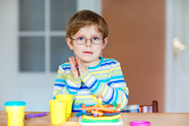 istock Smiling preschool kid boy having fun with dough, colorful modeling compound clay. Creative leisure with children. during corona virus quarantine staying at home. Shelter in place, lockdown concept, 1305942411