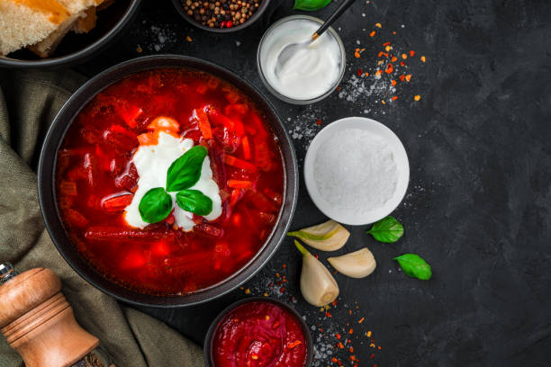 ukrainische traditionelle borscht mit saurer sahne und knoblauch auf schwarzem hintergrund nahaufnahme - tomato soup red basil table stock-fotos und bilder