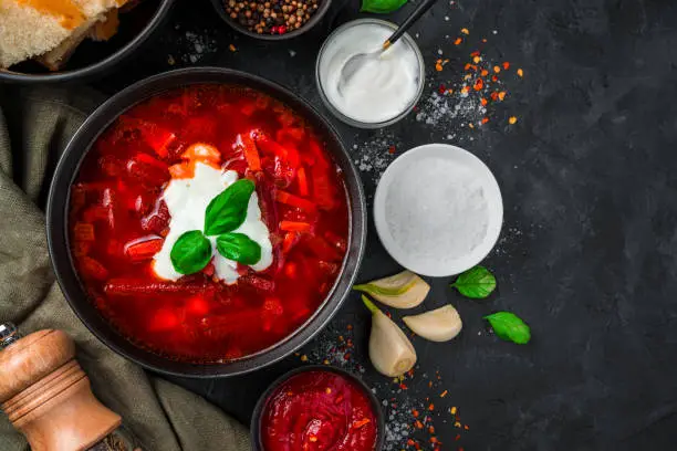 Ukrainian traditional borscht with sour cream and garlic on a black background close-up. Top view with copy space.