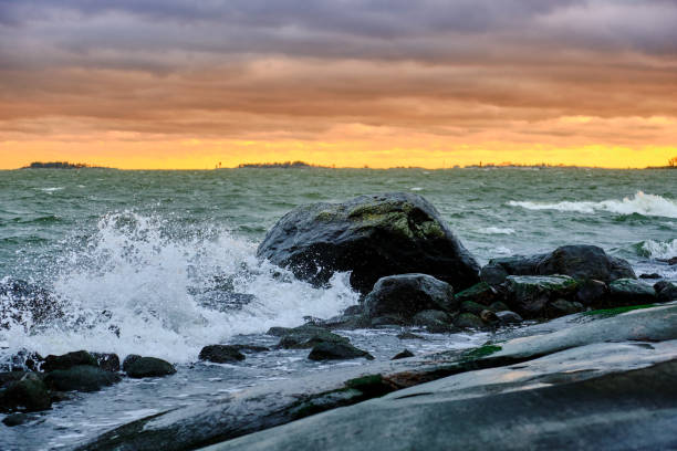 Sea waves rolling on stones, cloudy sunset sky on the background. The Nordic nature. Baltic sea.