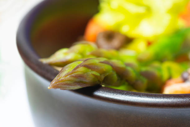 Close-up of pottery bowl with dish of asparagus and other vegetables