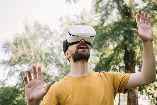 Excited man using virtual reality glasses standing outdoors