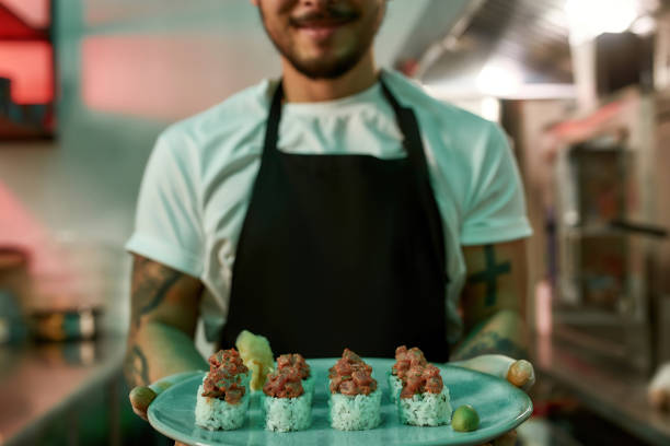 istock Male chef holding sushi in his hands 1305945419