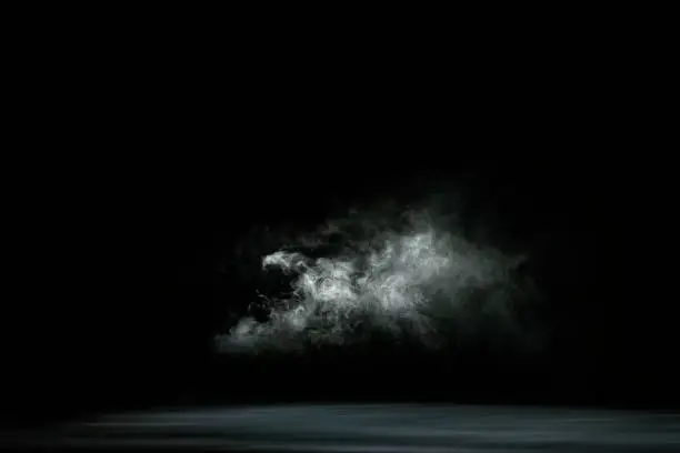 Photo of Dry white ice smoke clouds fog empty stage textured. Isolated black background.