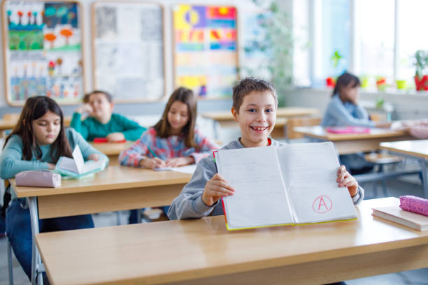 istock Happy schoolboy showing his A grade on a test at elementary school 1305947759