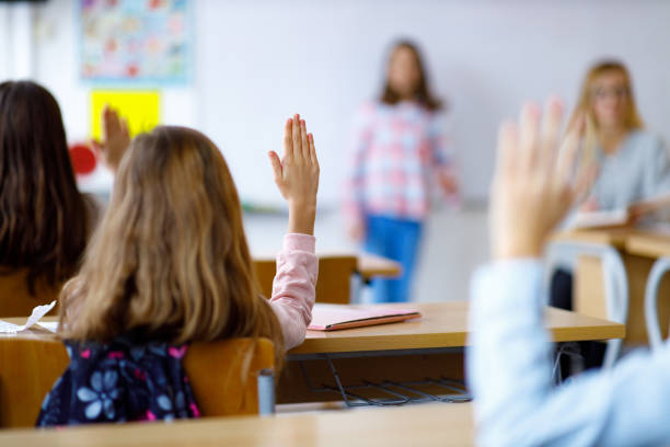istock Children whit hands raised in the classroom 1305950420