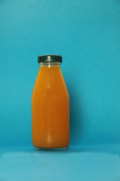 istock bottle of mango juice isolated on blue background 1305953879