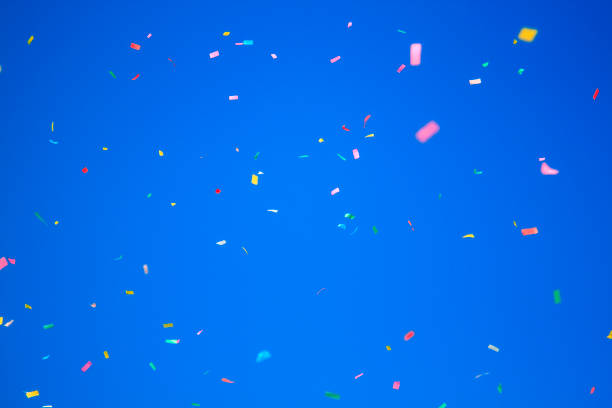 istock multicolored confetti on clear blue sky background. Concept of h 1305953978