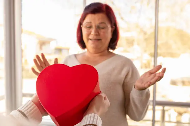 Photo of woman giving  gift box to her mother. Mother's day. Happy family moments at home.