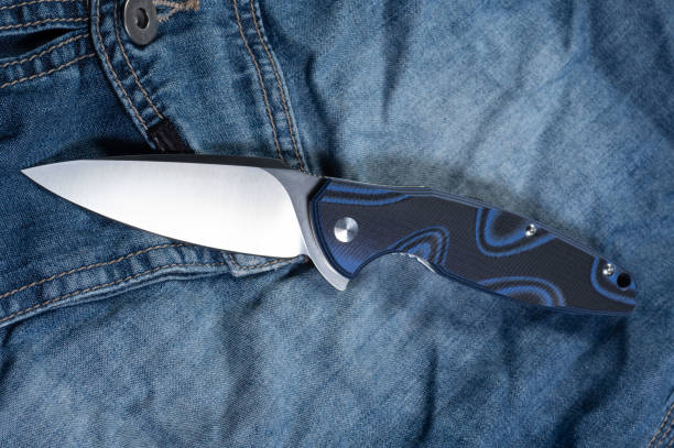 istock A casual folding knife rests on jeans. Knife with a blue handle. 1305956175