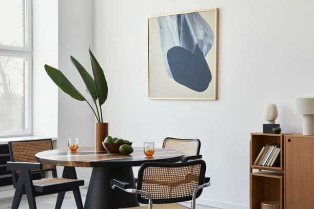 istock Stylish composition of dining room interior with design table, modern chairs, decoration, tropical leaf in vase, fruits, bookcase, abstract mock up paintings and elegant accessories in home decor. 1305956859