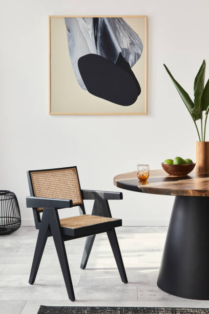 istock Stylish composition of dining room interior with design table, modern chairs, decoration, tropical leaf in vase, fruits, carpet, abstract mock up paintings and elegant accessories in home decor. 1305956885