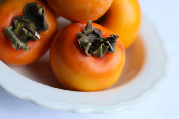 istock Fresh Ripe Persimmons on a White Classic Design Plate, Paradise Palms 1305958260