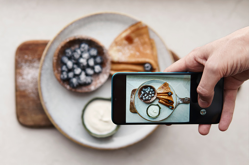 Hands taking photo of pancakes with smartphone
