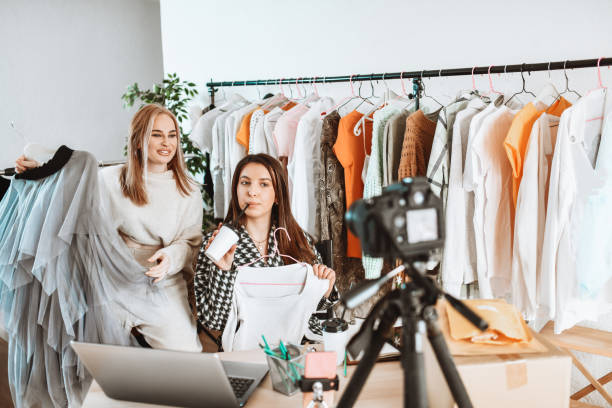 istock Smiling Female Vendors Presenting Their Clothes Store During Online Vlog 1305963231